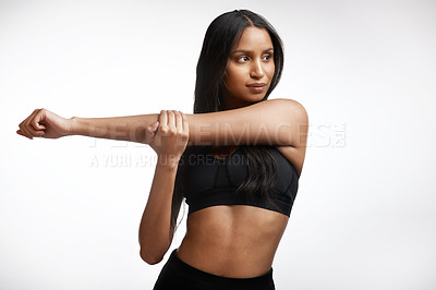 Buy stock photo Studio shot of a sporty young woman stretching her arms against a white background