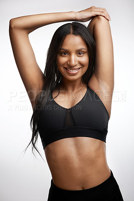 Buy stock photo Studio portrait of a sporty young woman stretching her arms against a white background