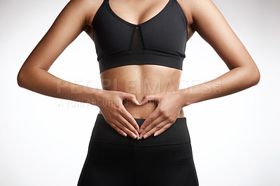 Buy stock photo Studio shot of an unrecognisable woman making a heart shape with her hands on her stomach against a white background