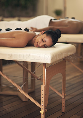 Buy stock photo Shot of a young woman getting a hot stone massage at a spa