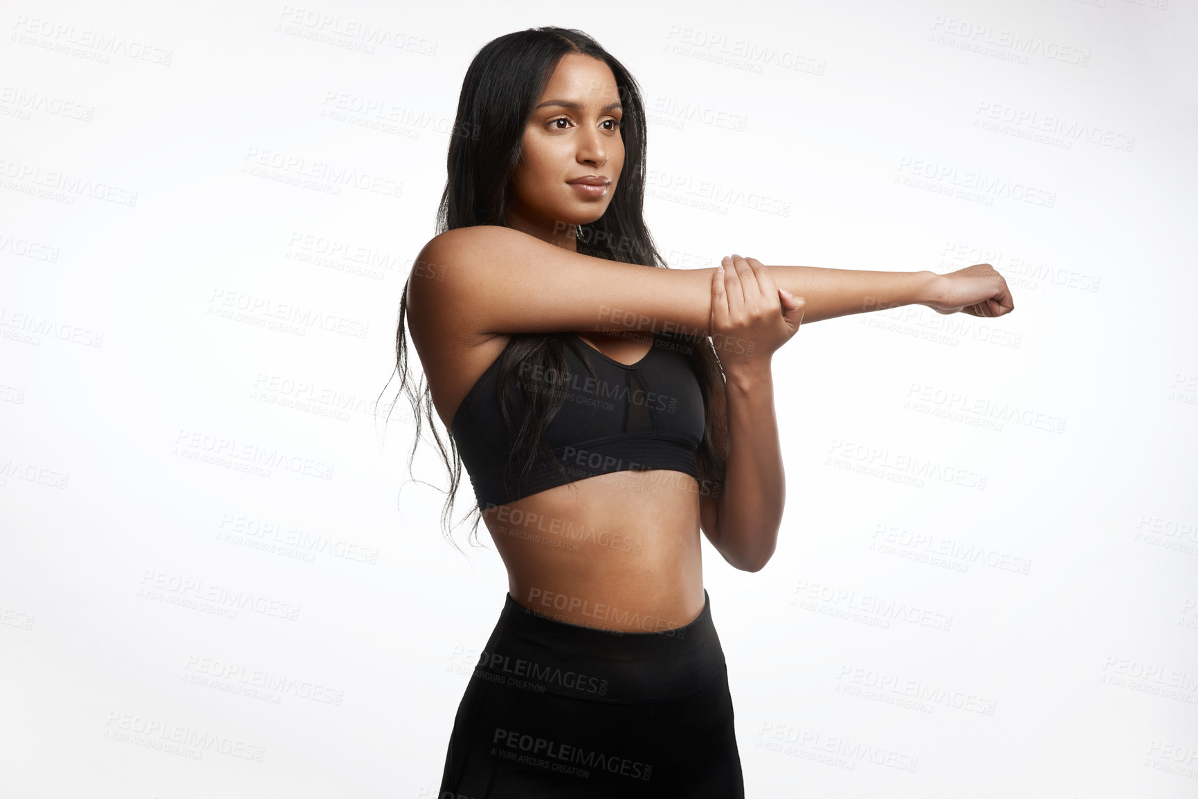 Buy stock photo Studio shot of a sporty young woman stretching her arms against a white background