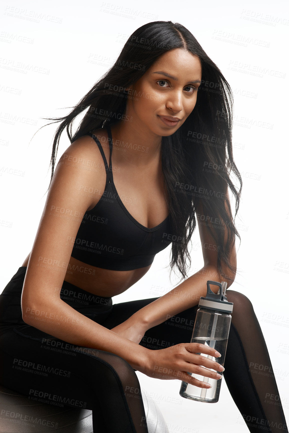 Buy stock photo Studio portrait of a sporty young woman holding a water bottle against a white background