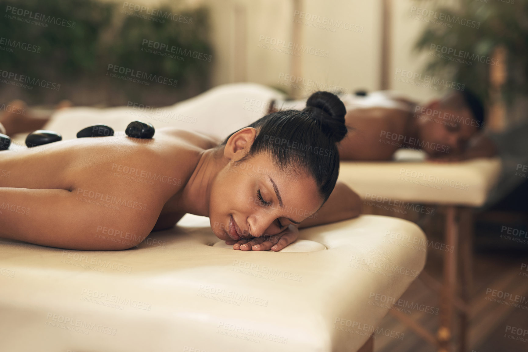 Buy stock photo Shot of a young woman getting a hot stone massage at a spa