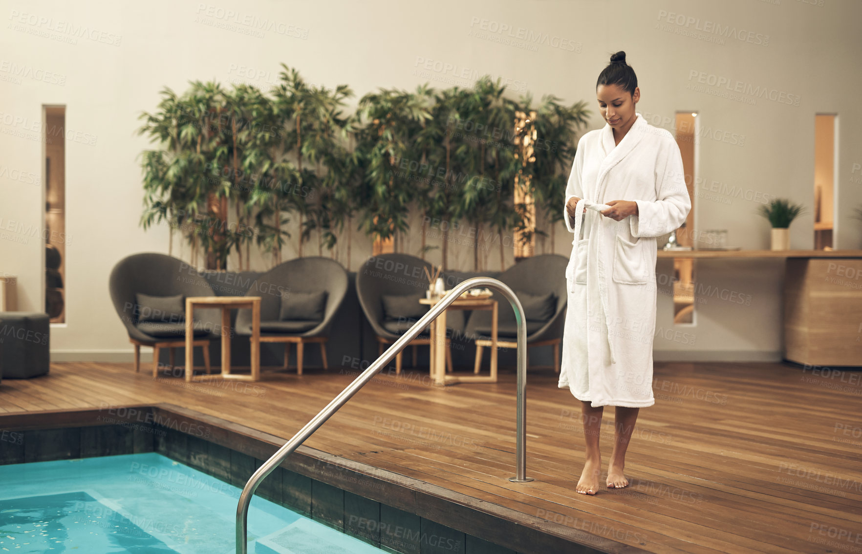 Buy stock photo Shot of a woman taking off her robe before getting into swimming pool at a spa resort