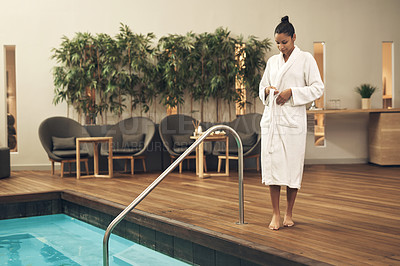 Buy stock photo Shot of a woman taking off her robe before getting into swimming pool at a spa resort