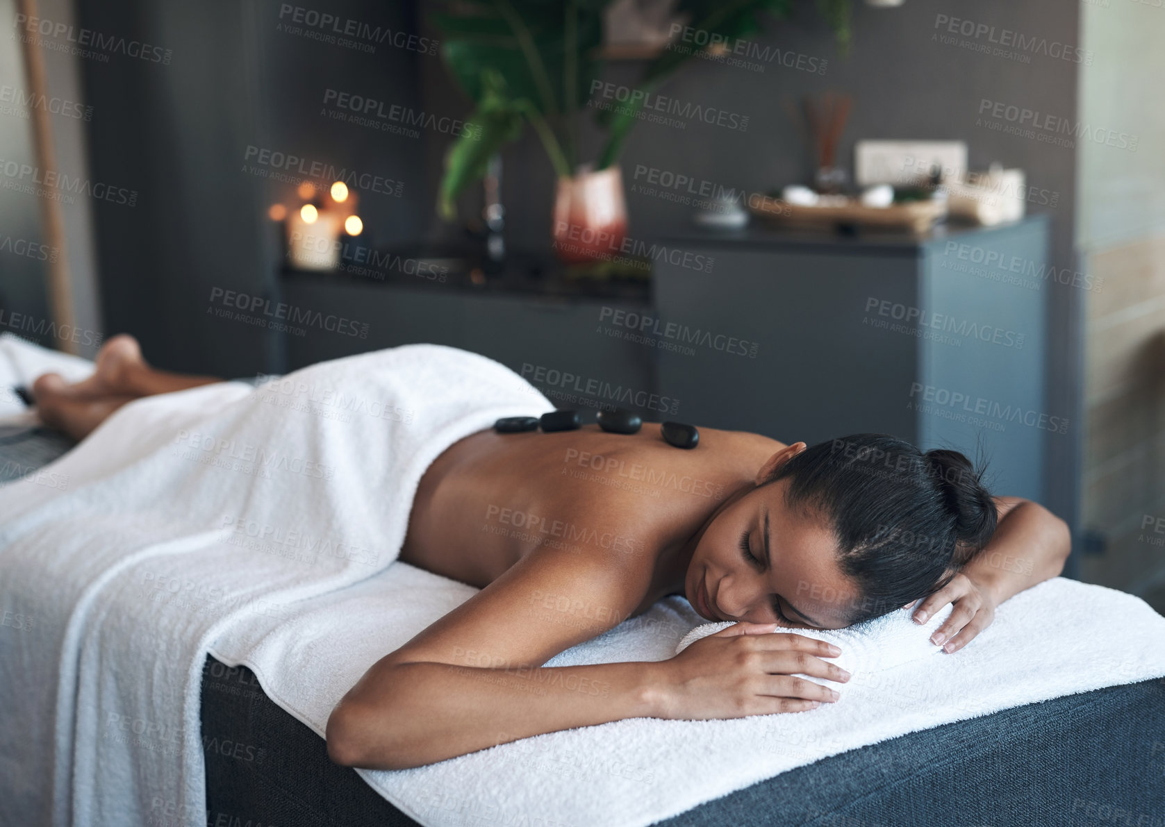 Buy stock photo Shot of a young woman getting a hot stone massage at a spa