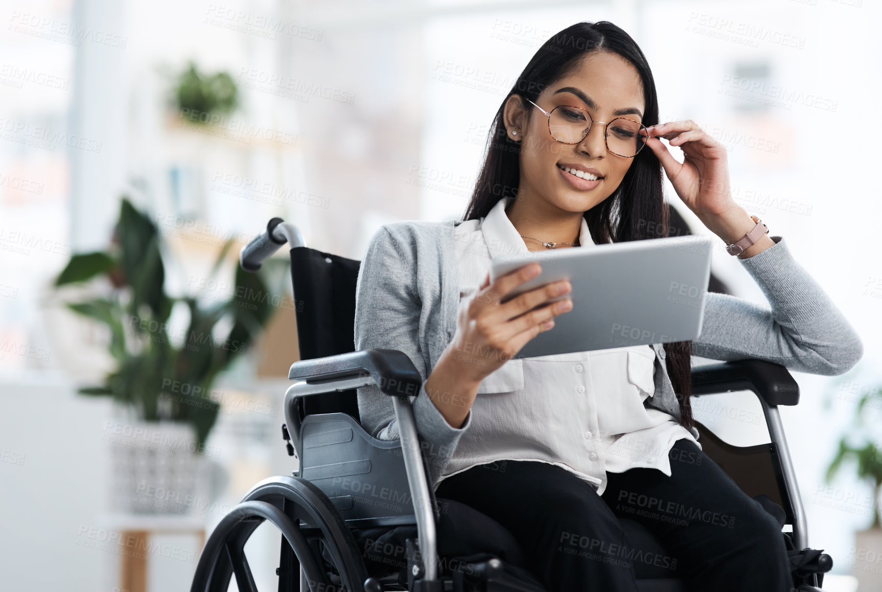 Buy stock photo Cropped shot of an attractive young businesswoman in a wheelchair using her tablet in the office