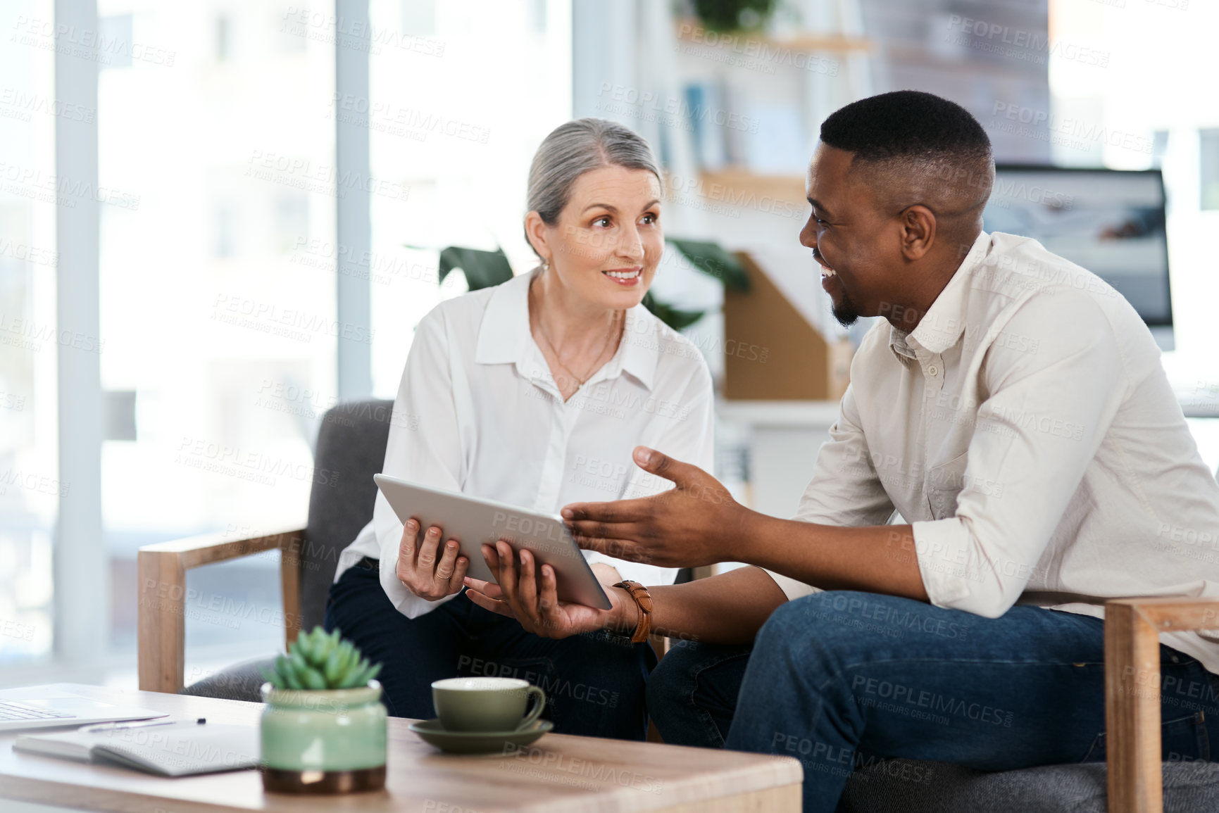 Buy stock photo Shot of two businesspeople using a digital tablet together in an office