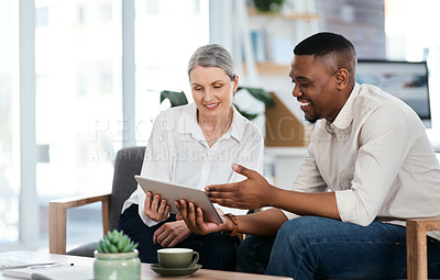 Buy stock photo Shot of two businesspeople using a digital tablet together in an office