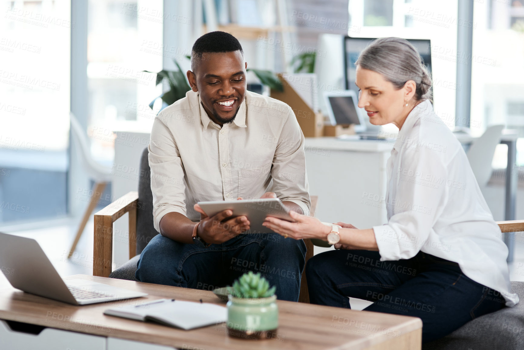 Buy stock photo Shot of two businesspeople using a digital tablet together in an office