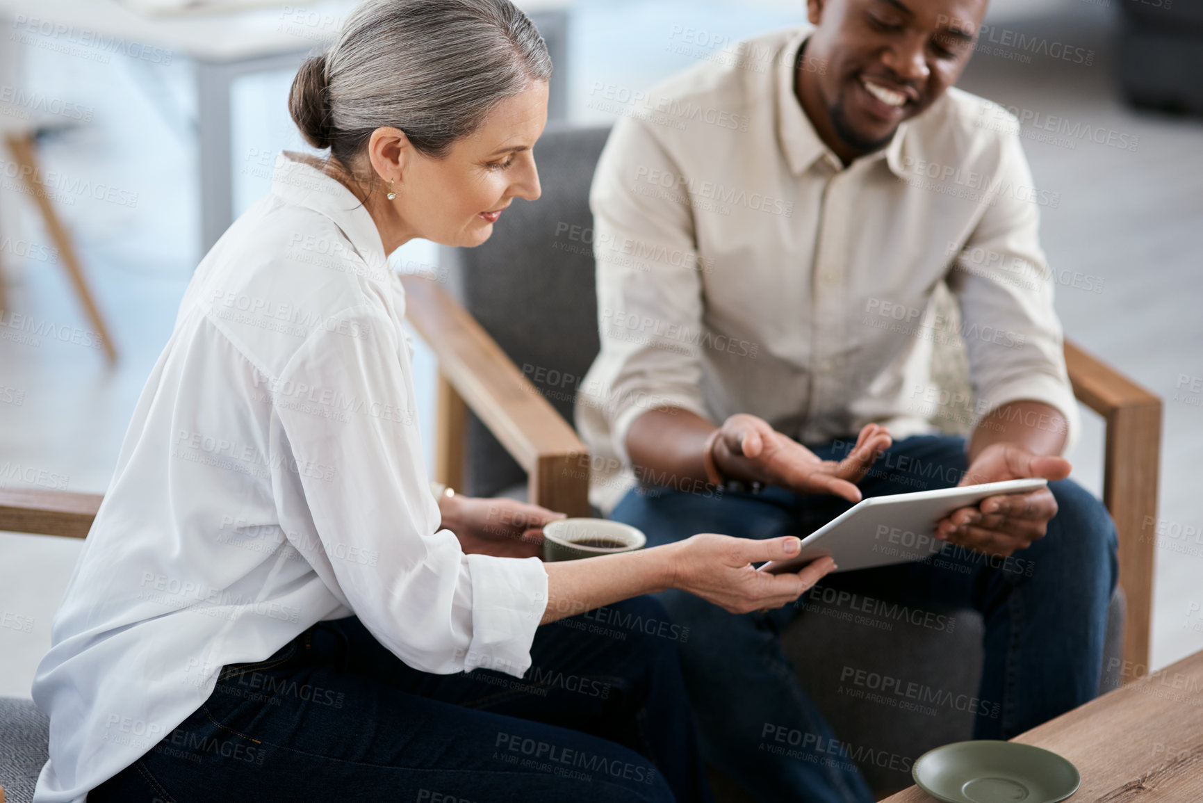 Buy stock photo Shot of two businesspeople using a digital tablet together in an office