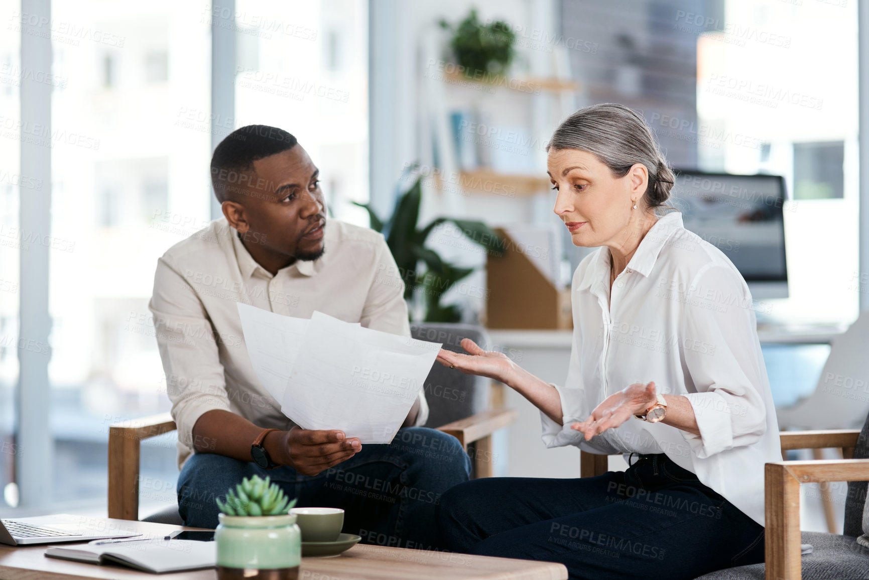 Buy stock photo Shot of a mature businesswoman shrugging while going through paperwork with a colleague in an office