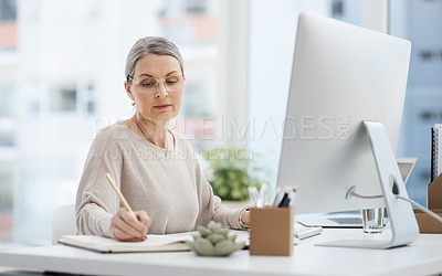 Buy stock photo Cropped shot of an attractive mature businesswoman making notes while working at her desk in the office