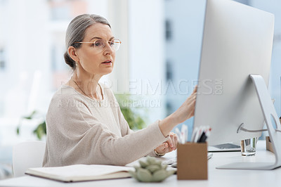 Buy stock photo Cropped shot of an attractive mature businesswoman working on a desktop at her desk in the office