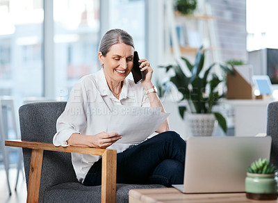 Buy stock photo Shot of a mature businesswoman talking on a cellphone while going through paperwork in an office