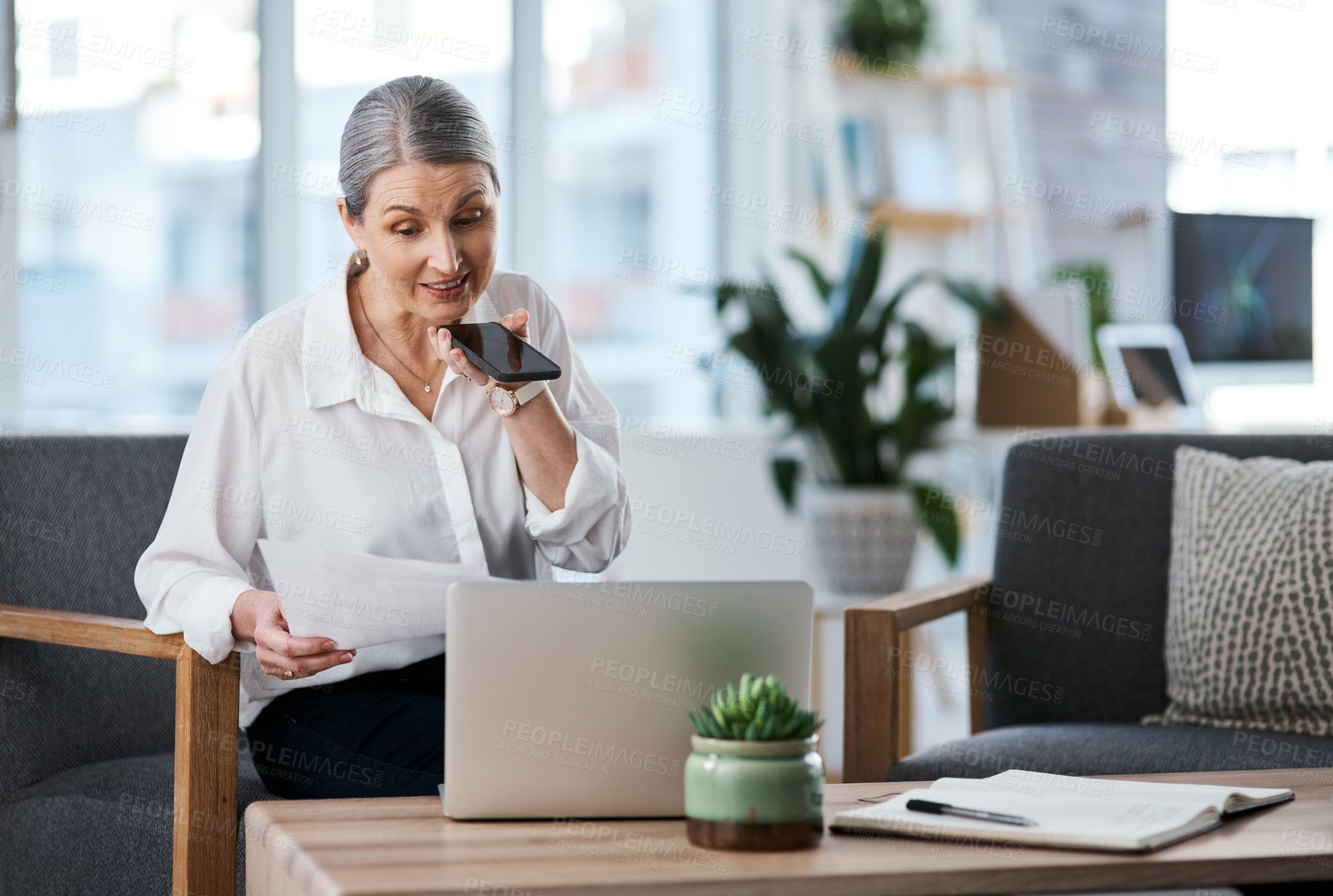 Buy stock photo Shot of a mature businesswoman talking on a cellphone while going through paperwork in an office