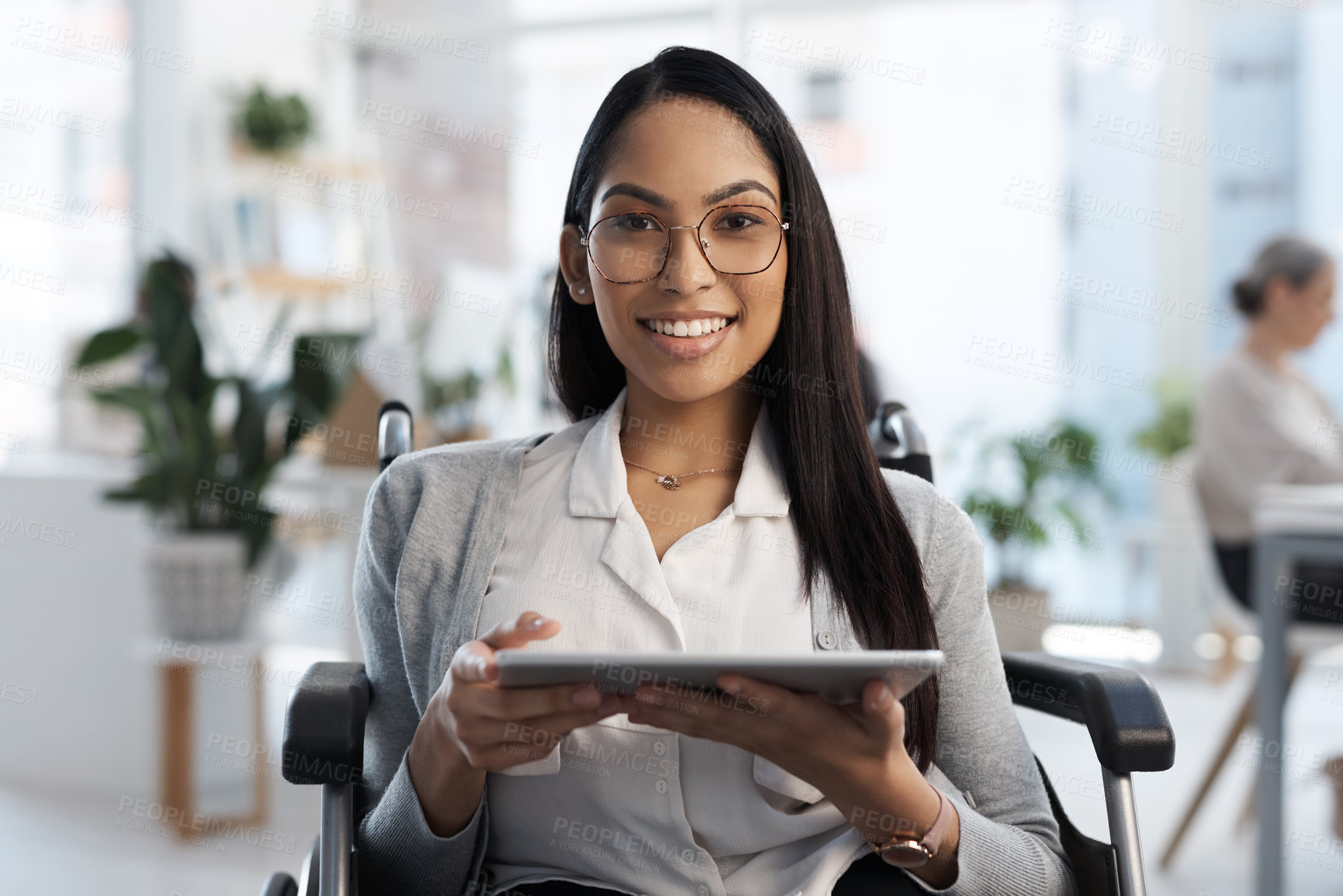 Buy stock photo Cropped portrait of an attractive young businesswoman in a wheelchair using her tablet in the office