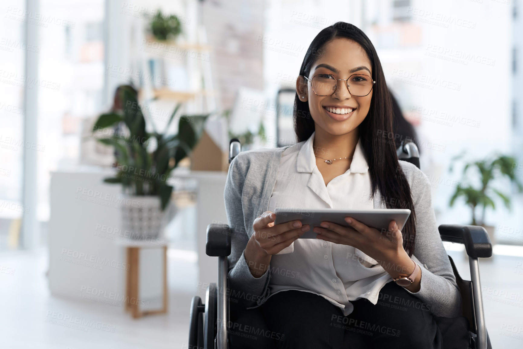 Buy stock photo Cropped portrait of an attractive young businesswoman in a wheelchair using her tablet in the office