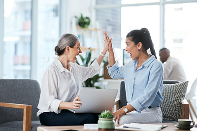 Buy stock photo Shot of two businesswomen giving each other a high five while working together in an office