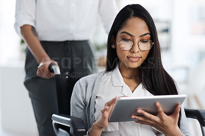 Buy stock photo Cropped shot of an attractive young businesswoman in a wheelchair using her tablet in the office