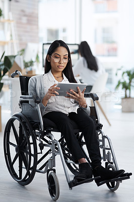 Buy stock photo Full length shot of an attractive young businesswoman in a wheelchair using her tablet in the office