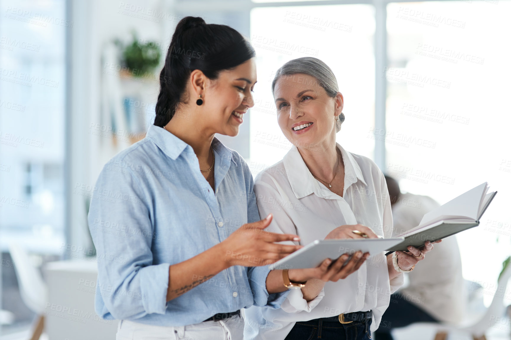 Buy stock photo Shot of two businesswomen using a digital tablet together in an office