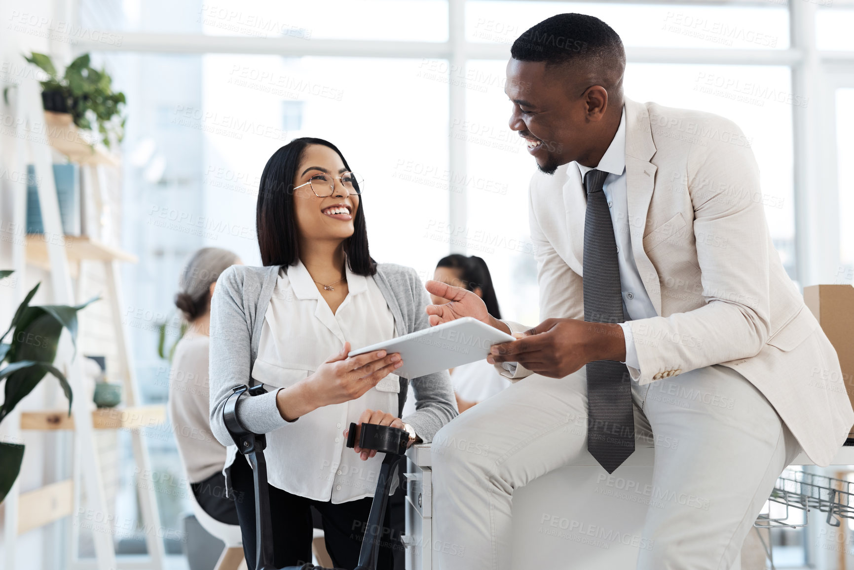 Buy stock photo Cropped shot of two young businesspeople discussing work over a digital tablet in their office