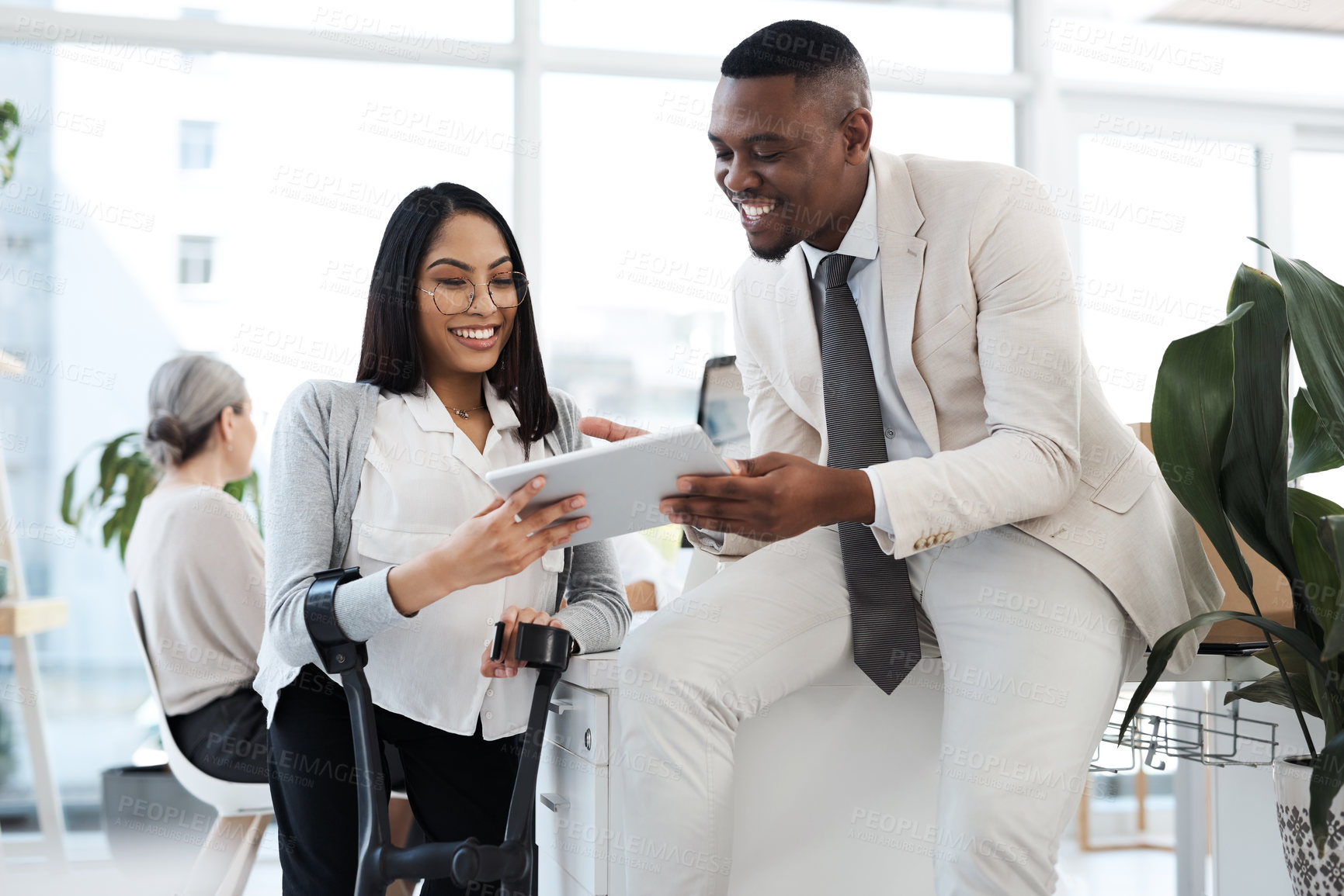 Buy stock photo Cropped shot of two young businesspeople discussing work over a digital tablet in their office