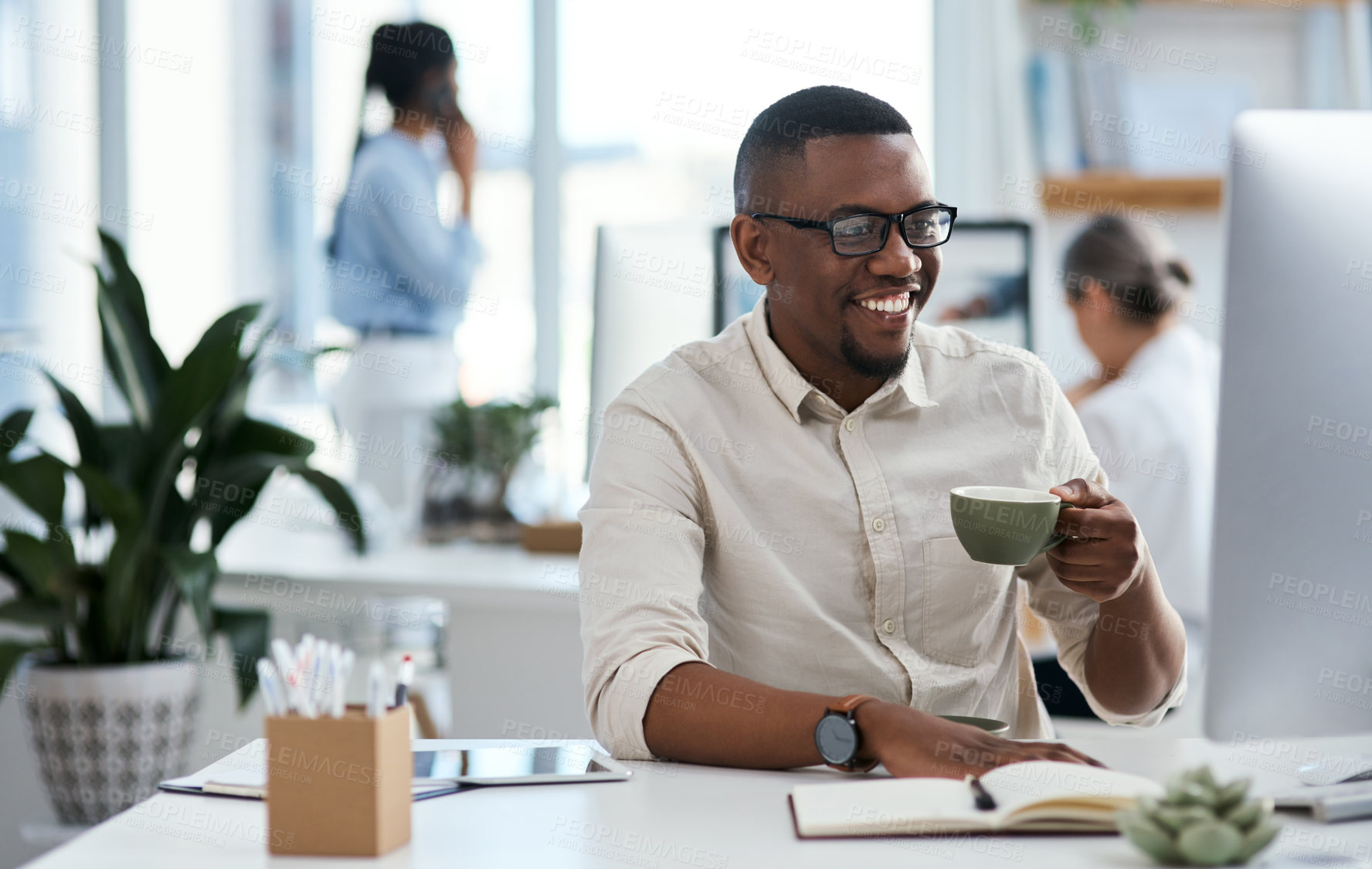 Buy stock photo Shot of a young businessman drinking coffee while working on a computer in an office