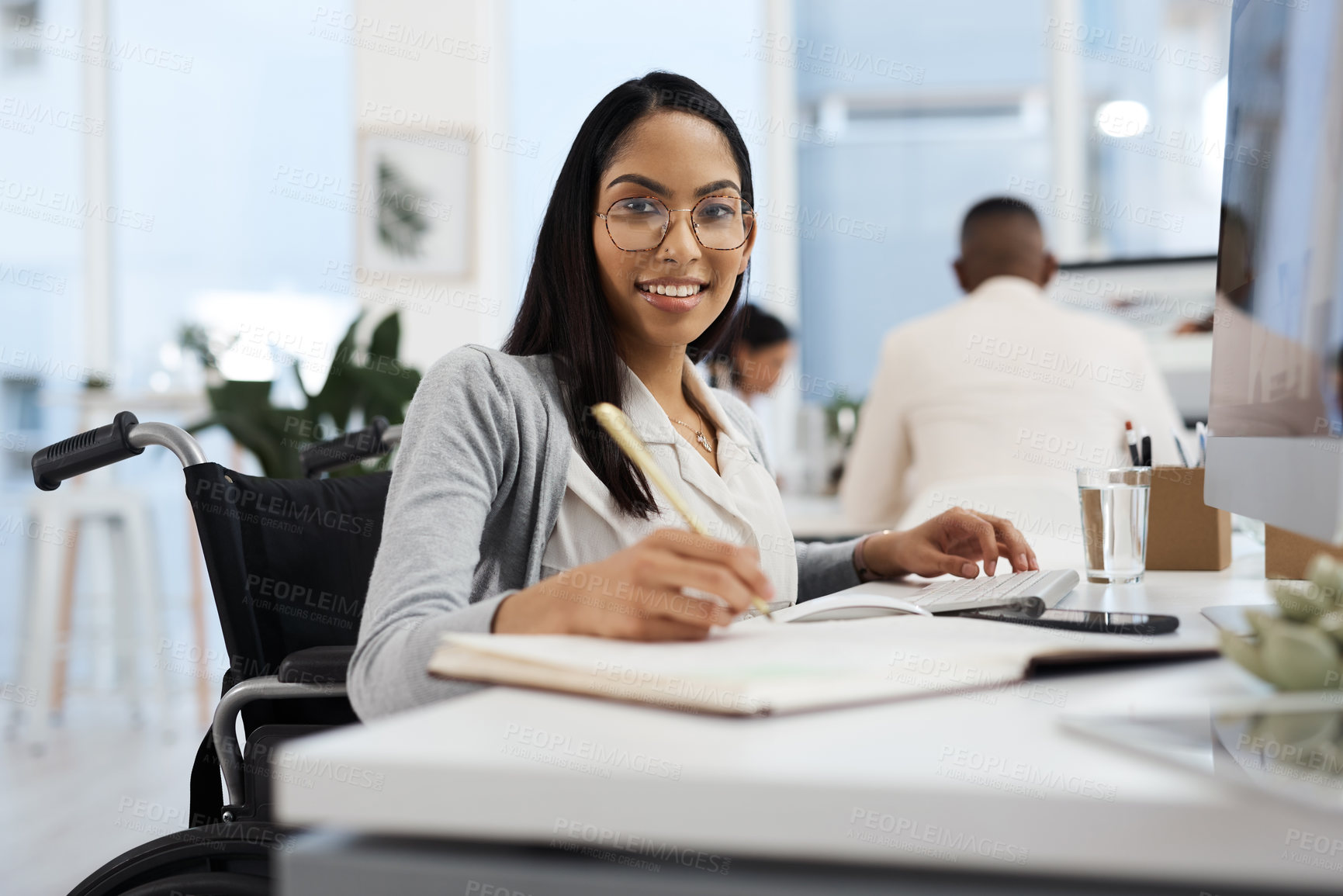 Buy stock photo Cropped portrait of an attractive young businesswoman in a wheelchair writing in her notebook while working in the office