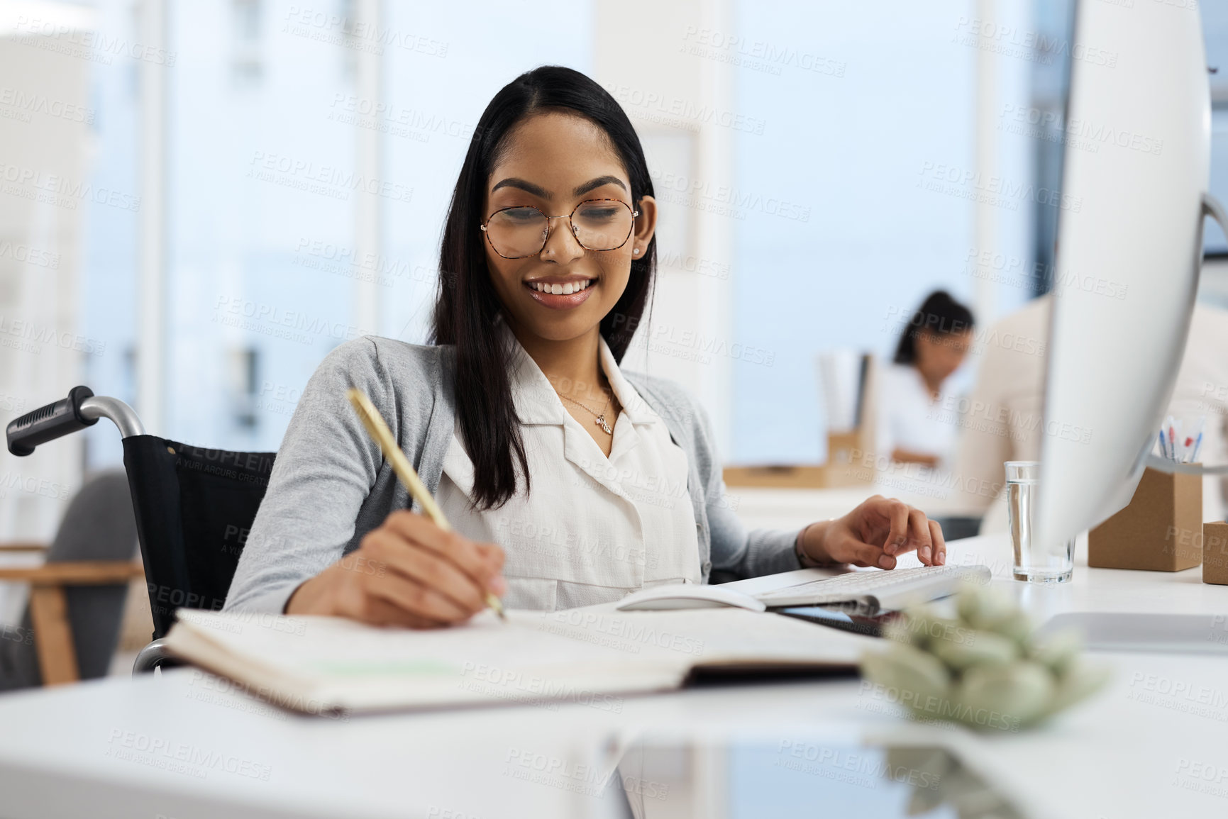 Buy stock photo Cropped shot of an attractive young businesswoman writing in her notebook while working in the office