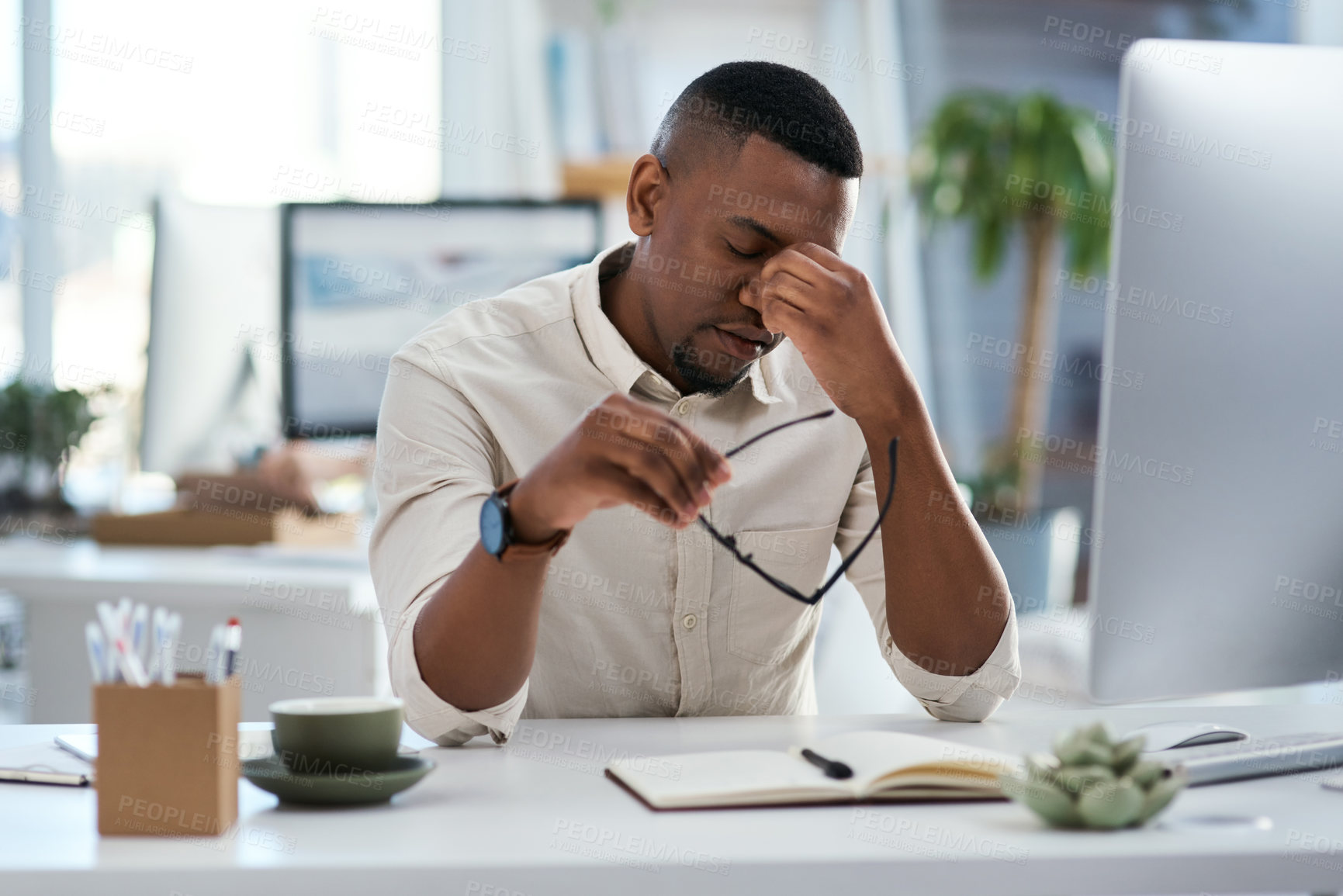 Buy stock photo Shot of a young businessman looking stressed out while working in an office