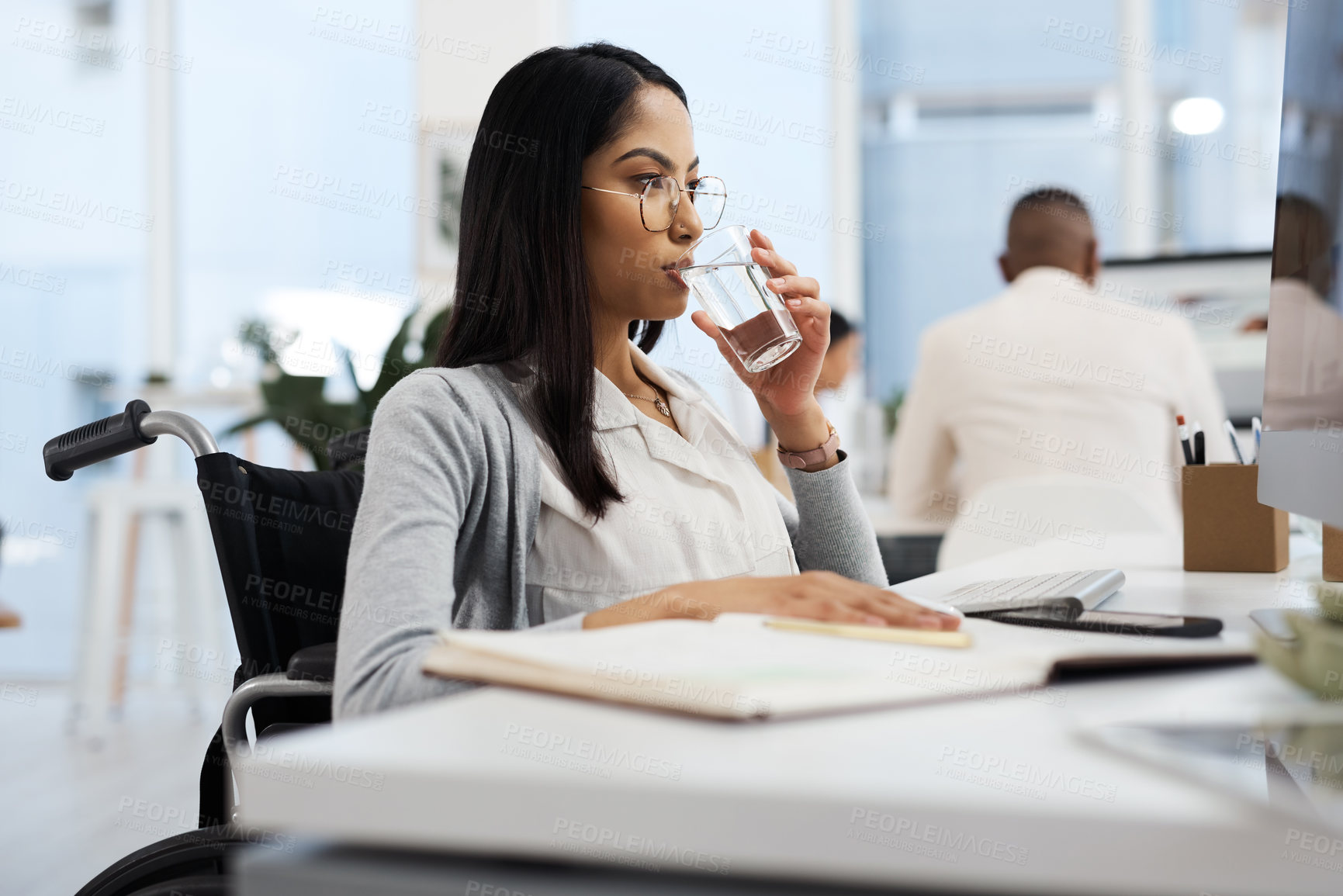 Buy stock photo Cropped shot of an attractive young businesswoman drinking water while working at her desk in the office