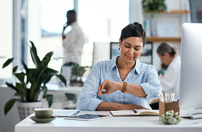Buy stock photo Shot of a young businesswoman checking the time on her wristwatch while working in an office
