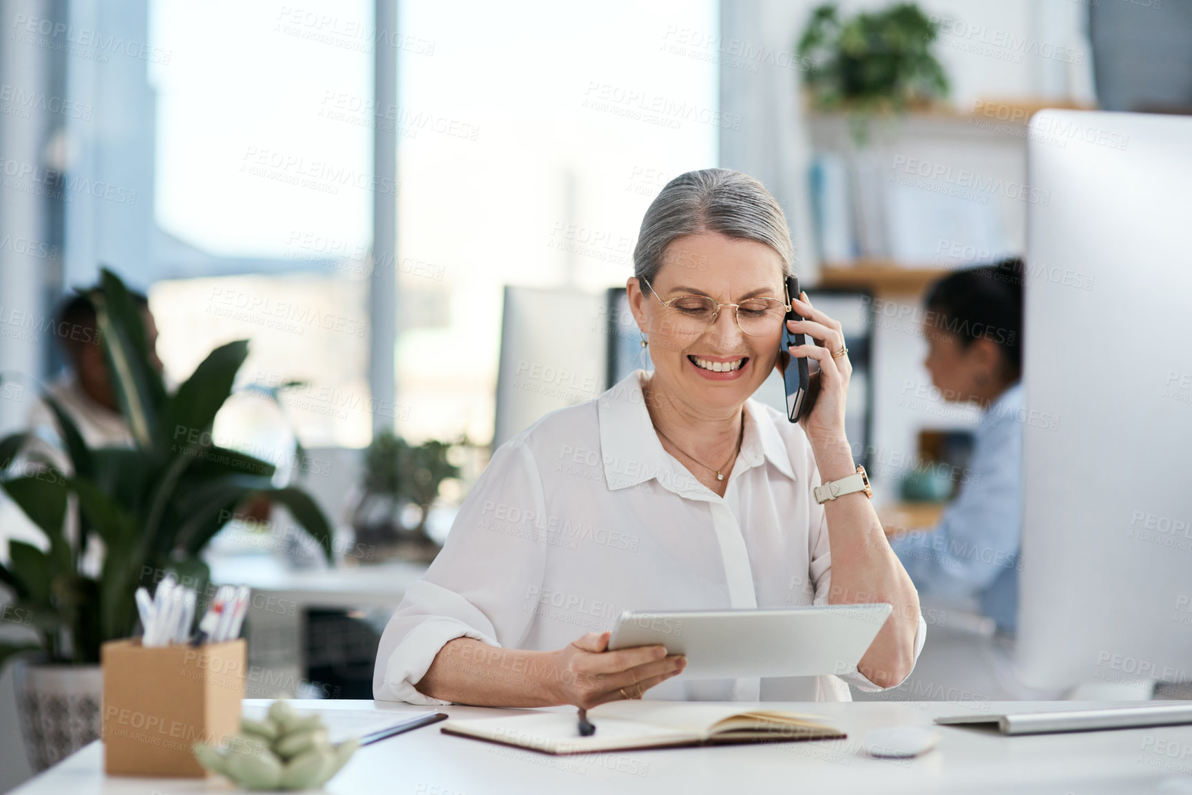 Buy stock photo Phone call, tablet and mature woman in office with smile, contact and creative planning at digital agency. Smartphone, designer or consultant at tech startup with online schedule in coworking space