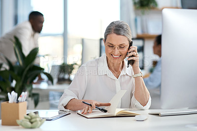 Buy stock photo Shot of a mature businesswoman talking on a cellphone while going through notes in an office