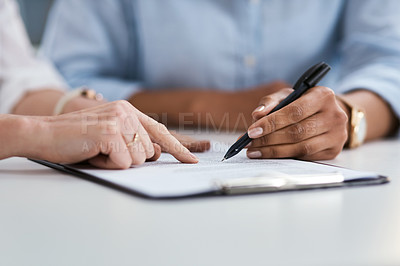 Buy stock photo Closeup shot of two unrecognisable businesswomen going through paperwork together in an office