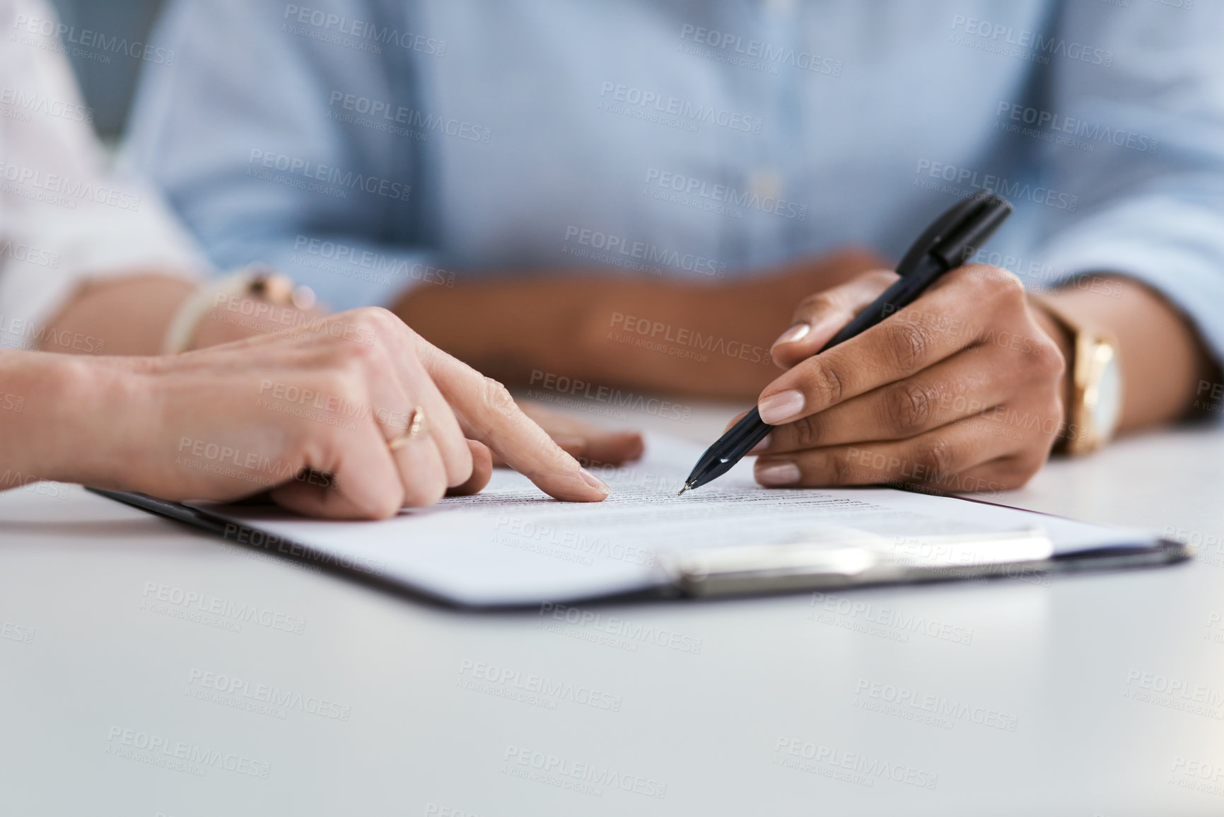 Buy stock photo Closeup shot of two unrecognisable businesswomen going through paperwork together in an office