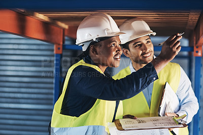 Buy stock photo Shot of two young contractors standing together and examining the scaffolding in the warehouse