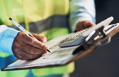 Buy stock photo Cropped shot of an unrecognizable contractor standing alone in the warehouse and writing on a document during stock-take