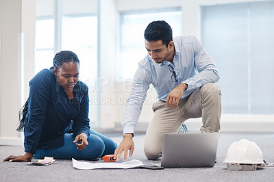 Buy stock photo Shot of a young architect talking to an interior designer while looking at a floor plan for the office