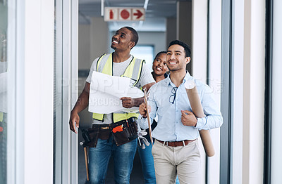 Buy stock photo Shot of a group of architects walking together and having a discussion about the room before they renovate