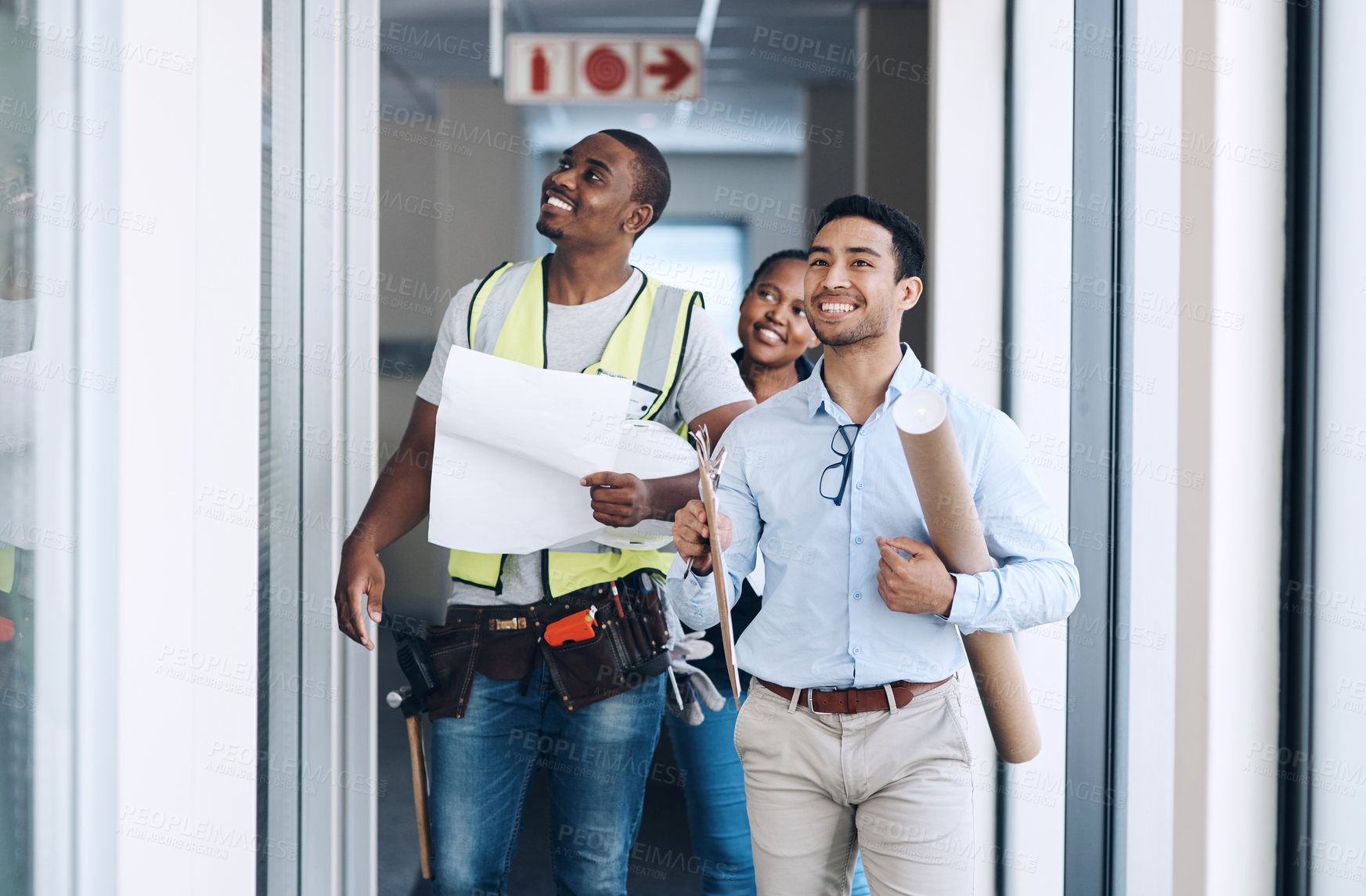 Buy stock photo Shot of a group of architects walking together and having a discussion about the room before they renovate