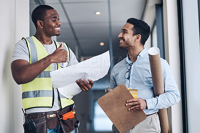 Buy stock photo Shot of two young architects standing together and having a discussion about the room before they renovate