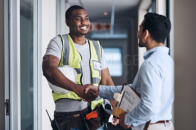 Buy stock photo Shot of two young architects standing together and shaking hands after a discussion about the room before they renovate