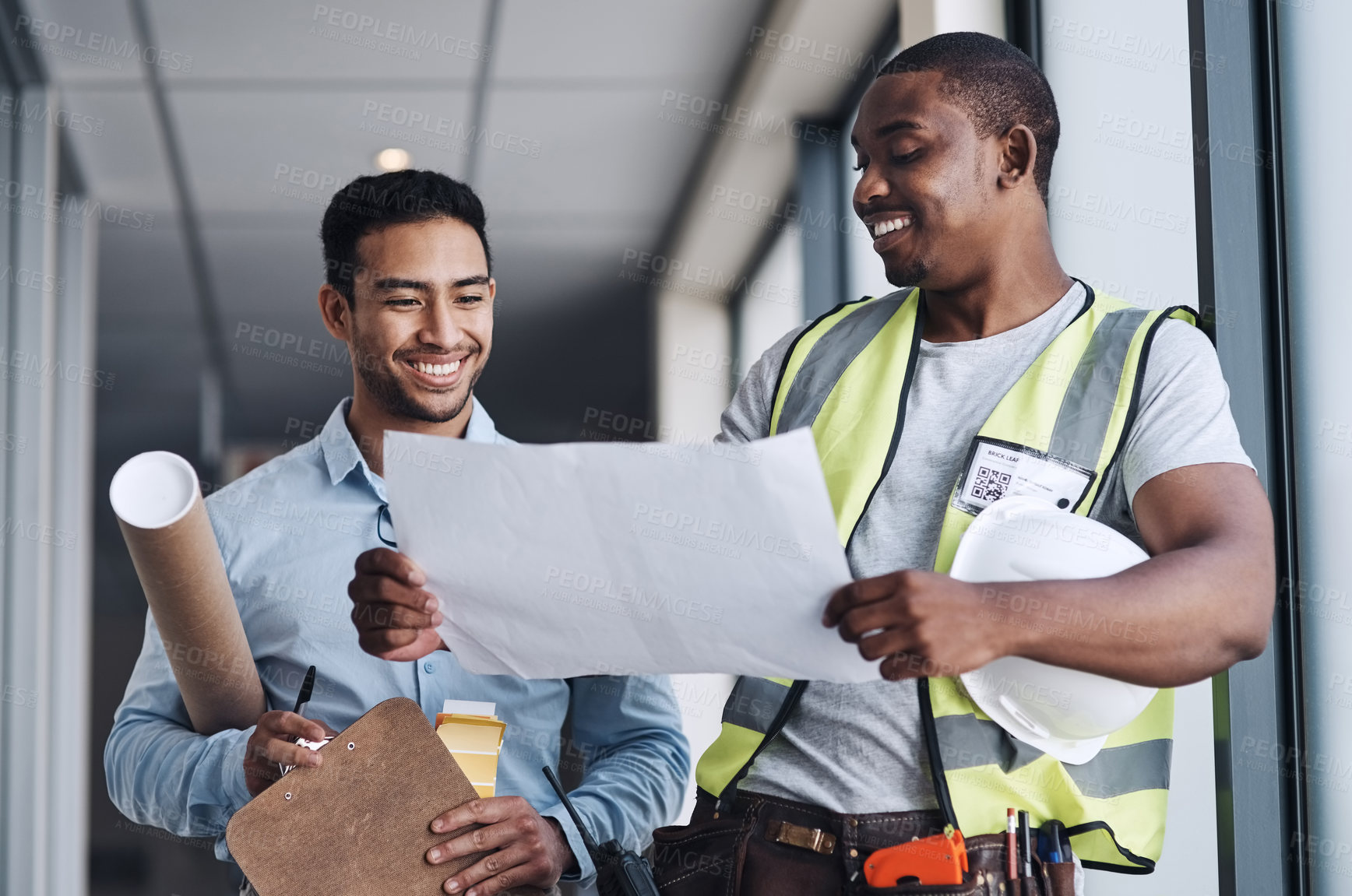 Buy stock photo Shot of two young architects standing together and having a discussion about the room before they renovate