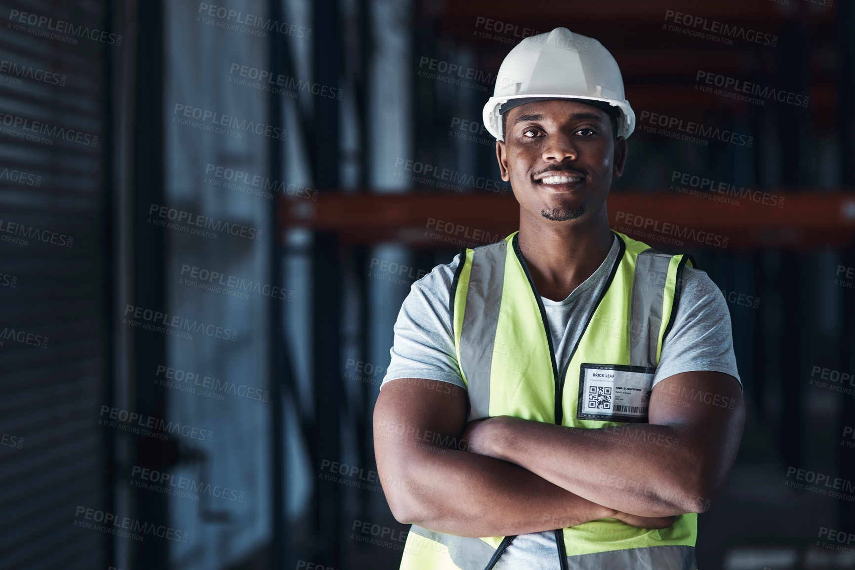 Buy stock photo Shot of a handsome young contractor standing alone in the warehouse with his arms crossed