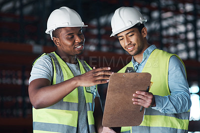 Buy stock photo Shot of two young contractors standing in the warehouse and having a discussion while looking at a clipboard