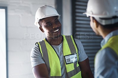 Buy stock photo Shot of two young contractors standing in the warehouse together and having a discussion