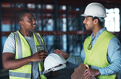 Buy stock photo Shot of two young contractors standing in the warehouse together and having a discussion